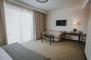 WłoszakowiceHotel Toscania的酒店客房配有床、沙发和电视。