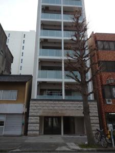 名古屋ケイアイコンホテルズ 久屋的公寓大楼前面有一棵树