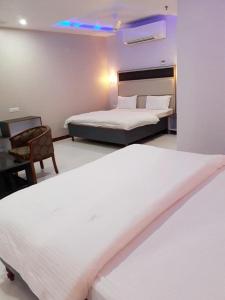 GiriakHotel Abhilasha的酒店客房,配有两张床和椅子