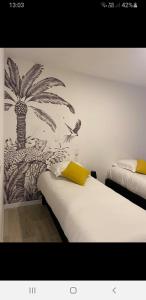 Fresnicourt-le-DolmenBelle vue D'Olhain的一间卧室配有两张床,并拥有棕榈树壁画