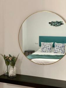 博罗尼亚Apartamentos Turísticos Carmencita的床上方墙上的镜子和枕头