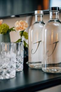 韦斯特兰Jaumann's Südwind Sylt的桌子上放着三瓶和玻璃杯,放着鲜花