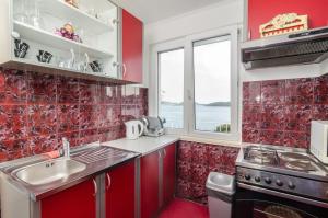 斯拉诺Apartment Giovani的红色的厨房设有水槽和炉灶
