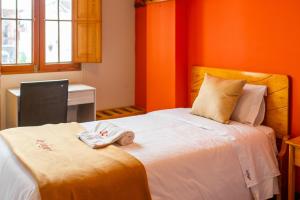 阿雷基帕Le Foyer Arequipa的一间卧室设有橙色的墙壁和一张带毛巾的床