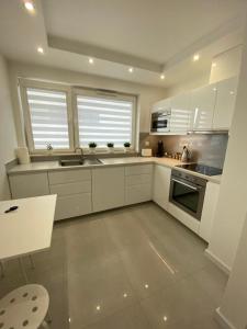 波兹南Flat4You的厨房配有白色橱柜、水槽和炉灶。