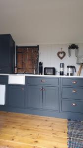 法弗舍姆The cosy hut的厨房配有蓝色橱柜和白色水槽
