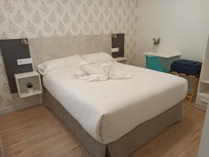 罗德里戈城Apartamentos Adarve的一间卧室配有一张带白色床单的大床
