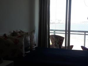 桑托斯Maravilhoso Apto Vista Mar Jacuzzi Wi Fi Pé Areia的卧室配有带枕头的床铺和窗户。