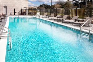 塔拉哈西Hyatt House Tallahassee Capitol University的一个带蓝色海水和躺椅的游泳池