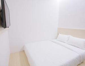 新山Minimalist Hotel的白色的床、白色枕头和电视