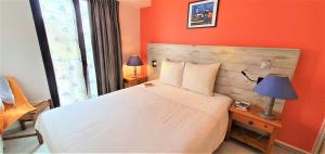 卡马雷Appart'Hôtel du Bout du Monde的一间卧室配有一张白色的床和橙色的墙壁