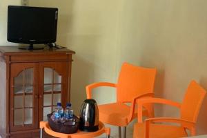 先达KoolKost near Budi Mulia Siantar的一间设有两把橙色椅子和电视的房间