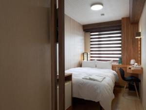 磐城PACIFICO Hotel and Spa的一间卧室配有一张床、一张书桌和一个窗户。