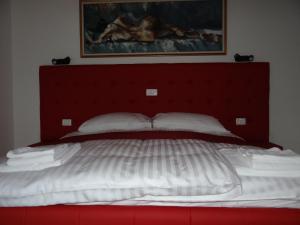 博德森特克Relax Center Olimian的一张大床,配有红色床头板和白色枕头