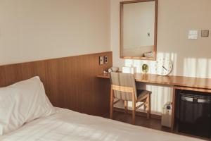 西归浦市Kenny Stay Jeju Mosulpo的酒店客房配有一张床和一张带镜子的书桌