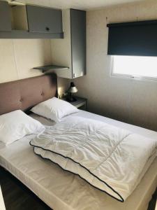 滨海贝尔克Mobil-home 4 personnes 400m de la mer的卧室内的一张大白色床,带有窗户
