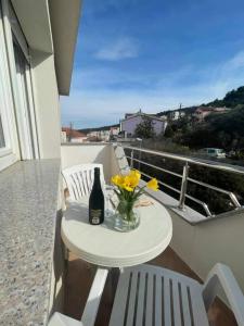 玛里纳Apartman & rooms Draga的阳台上的桌子上放着一瓶葡萄酒和鲜花