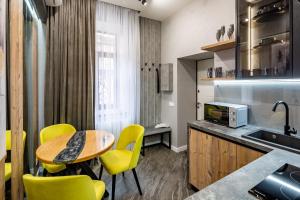 利沃夫Alfa Apartments Kulisha 12的厨房配有黄色的椅子、桌子和水槽