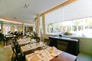 科尔多瓦Quorum Córdoba Hotel, Resort Urbano的餐厅设有桌椅和大窗户。