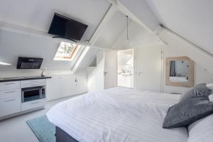 坎珀兰Slapen bij Jansz的一间白色卧室,配有一张大床和一台电视
