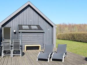 诺尔赫鲁普12 person holiday home in Hadsund的甲板上的一组椅子,有一座建筑