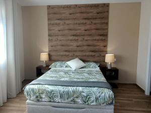 OterEl Mirador de Oter的一间卧室配有一张带木制床头板的床和两盏灯。