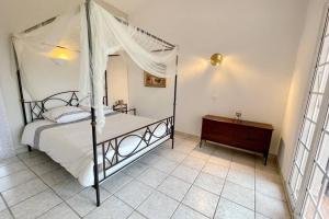 昂蒂布Rose d'Antibes的一间卧室配有一张天蓬床和木制梳妆台。