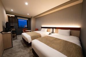东京Almont Hotel Nippori的酒店客房设有两张床和电视。