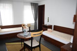 萨尔茨韦德尔Hotel & Restaurant Aragwi的客房设有两张床和一张桌子及椅子