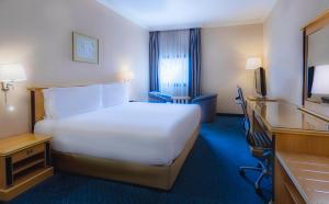 延布延布假日旅馆的酒店客房设有一张白色大床和一张书桌