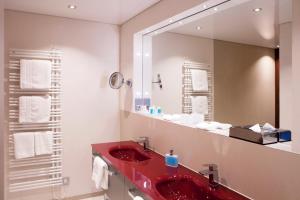 瓦尔德布龙仕维策尔公园酒店的一间带红色水槽和镜子的浴室