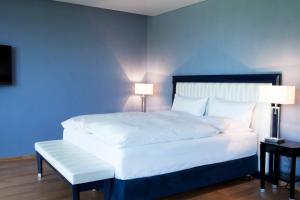 瓦尔德布龙仕维策尔公园酒店的一间卧室配有一张白色大床和蓝色的墙壁