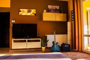 扎马迪全景公寓的客厅配有平面电视和吉他。