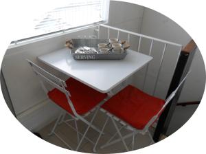 莱利斯塔德胡戈米德尔2号住宿加早餐旅馆的一张带两把红色椅子的小白色桌子和窗户