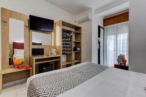 里乔内Hotel Grazia Riccione的一间带大床和电视的卧室