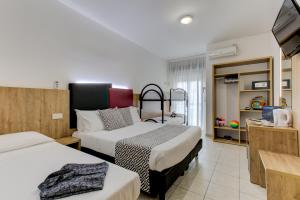 里乔内Hotel Grazia Riccione的酒店客房设有两张床和电视。