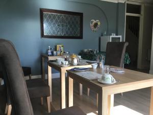 洛斯托夫特The Coventry Guest House的用餐室配有2张木桌和椅子