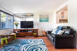 圣雷莫圣雷莫放松度假屋的客厅配有黑色真皮沙发和平面电视。