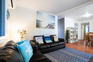 圣雷莫圣雷莫放松度假屋的客厅配有黑色真皮沙发和蓝色枕头。