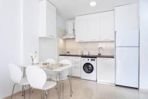 圭马尔港Apartamento Dulce Bea的白色的厨房配有桌子和白色家电