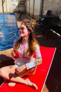 达戈米斯Отель Колизей的坐在游泳池旁红垫上的女人