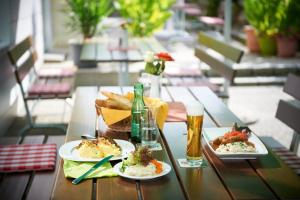 海格-安豪斯奥克米腾多尔坲宾馆的一张桌子,上面放着两盘食物和两杯啤酒
