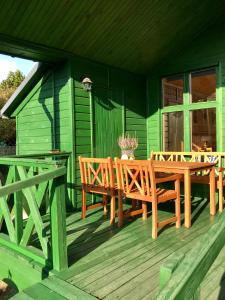 德兹维济诺Domek Green Dźwirzyno的绿色的房子,甲板上配有木桌和椅子