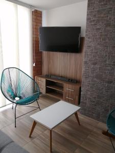 圣希尔Hermoso y Cómodo Apartamento--Excelente Ubicación的客厅配有电视、椅子和桌子