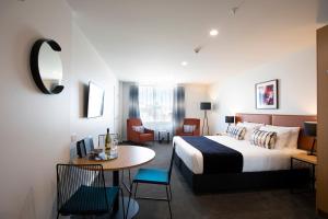 陶朗加Quest Tauranga Central的酒店客房带一张床、一张桌子和椅子