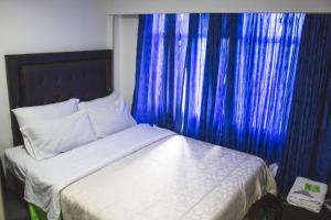 波哥大Hotel Punto 100的一间卧室配有一张蓝色窗帘的床