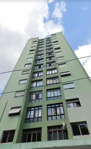 圣保罗Apartamento aconchegante com estacionamento na 25 de março的一座高大的绿色建筑,有许多窗户