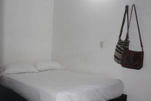 麦德林Hospedaje Primavera的白色的卧室配有一张床,墙上挂着钱包