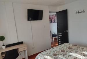 波哥大CASA AVILA - Apartamento amoblado 1 - Villa Alsacia的一间卧室配有一张床和一张书桌,墙上配有电视。
