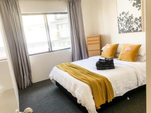 珀斯Spacious Homely Apartment Close to Everything的一间卧室配有一张带黄色枕头的床和一扇窗户